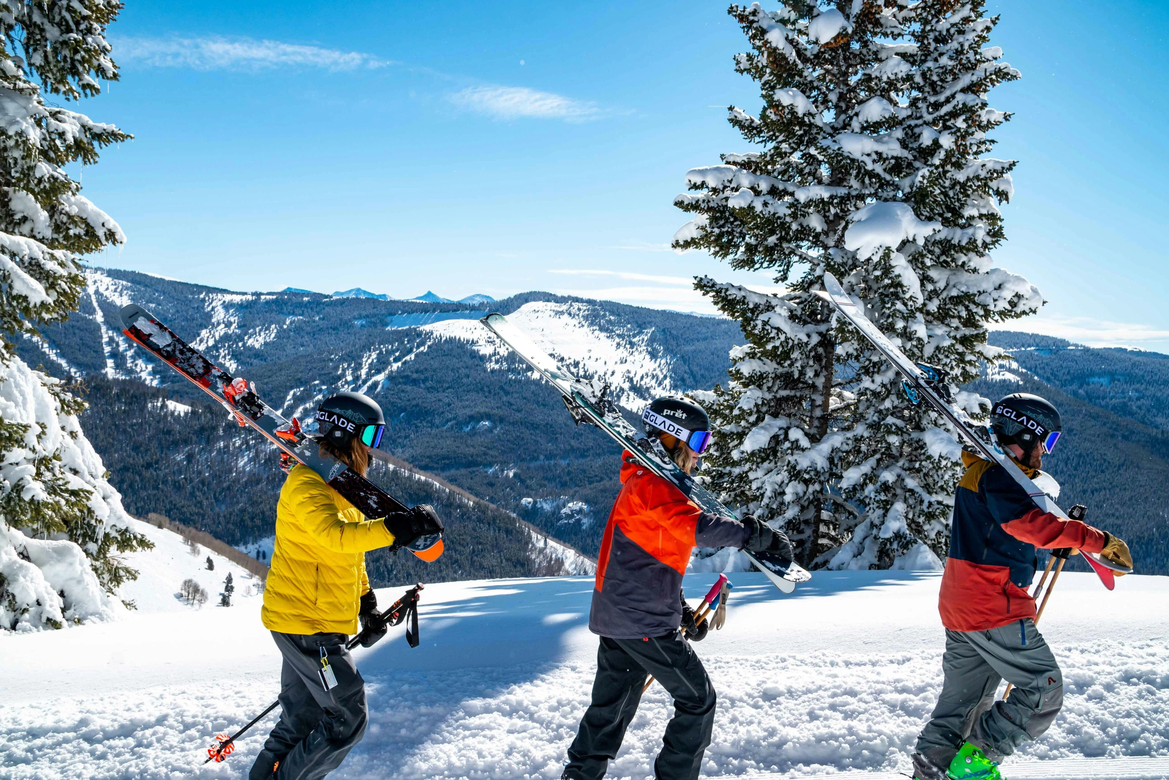 Skier carving on a mountain slope dressed in a white helmet and goggles with a blue jacket and red pants.